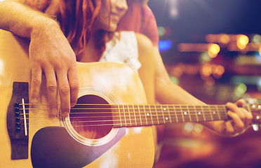 Image showing close up of couple with guitar over night lights