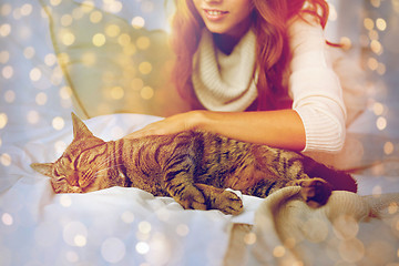 Image showing happy young woman with cat lying in bed at home