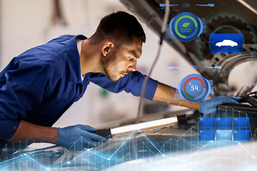 Image showing mechanic man with lamp repairing car at workshop