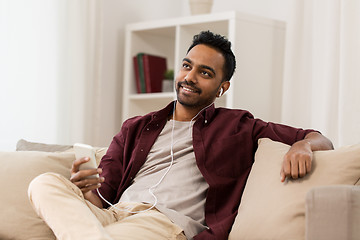 Image showing man in earphones listening to music on smartphone