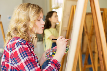 Image showing girl with easel painting at art school studio