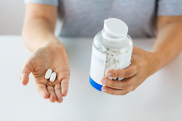 Image showing close up of hands holding medicine pills and jar