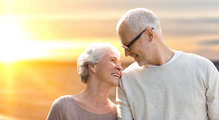 Image showing happy senior couple over sunset background