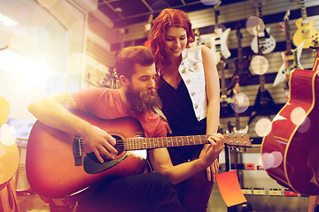 Image showing couple of musicians playing guitar at music store