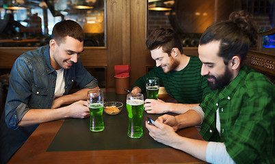 Image showing friends with smarphones and green beer at pub