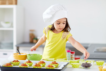 Image showing little girl in chefs toque baking muffins at home