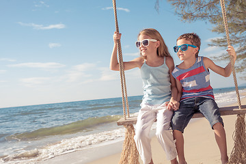 Image showing Two happy little children playing on the beach at the day time.