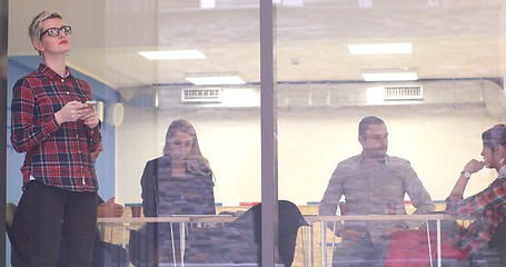 Image showing Business Woman Looking Through A Window And using On A Cell Phon