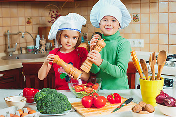 Image showing happy family funny kids are preparing the a fresh vegetable salad in the kitchen