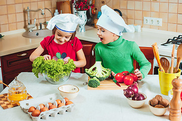 Image showing happy family funny kids are preparing the a fresh vegetable salad in the kitchen