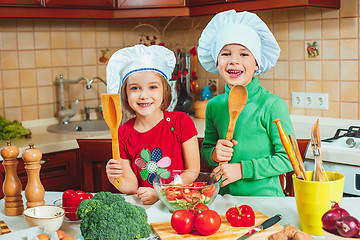 Image showing happy family funny kids are preparing the a fresh vegetable salad in the kitchen