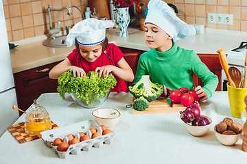 Image showing happy family funny kids are preparing the a fresh vegetable salad in the kitchen