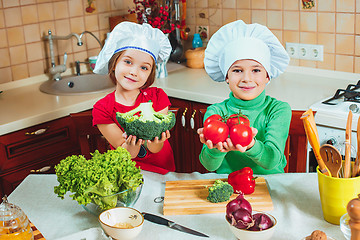 Image showing happy family funny kids are preparing the a fresh vegetable salad in the kitchen