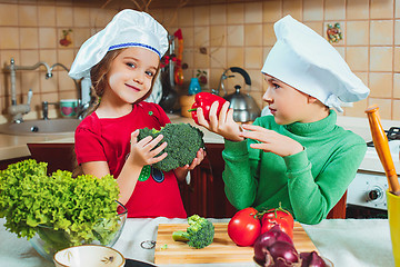 Image showing happy family funny kids are preparing the a fresh vegetable salad in the kitchen