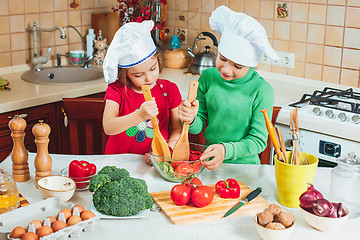 Image showing happy family funny kids are preparing the a fresh vegetable salad in the kitchen