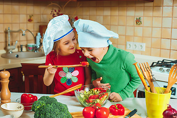 Image showing happy family funny kids are preparing the a fresh vegetable salad in the kitchen