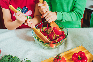 Image showing happy family funny kids are preparing the a fresh vegetable salad in the kitchen