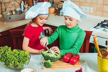 Image showing happy family funny kids are preparing the a fresh vegetable salad in the kitchen