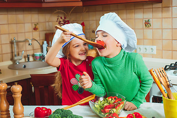 Image showing happy family funny kids are preparing the a fresh vegetable salad in the kitchen