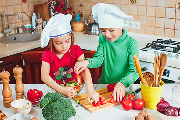 Image showing happy family funny kids are preparing the a fresh vegetable salad in the kitchen