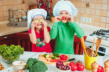 Image showing happy family funny kids are preparing the a fresh vegetable salad in the kitchen