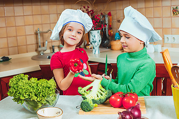 Image showing happy family funny kids are preparing the a fresh vegetable salad in the kitchen