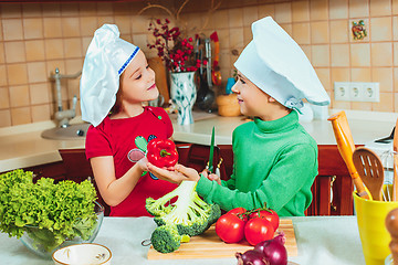 Image showing happy family funny kids are preparing the a fresh vegetable salad in the kitchen