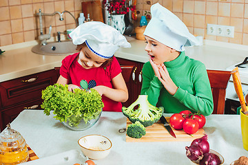 Image showing happy family funny kids are preparing the a fresh vegetable salad in the kitchen