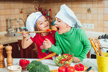 Image showing happy family funny kids are preparing the a fresh vegetable salad in the kitchen