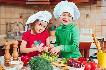 Image showing happy family funny kids are preparing the a fresh vegetable salad in the kitchen