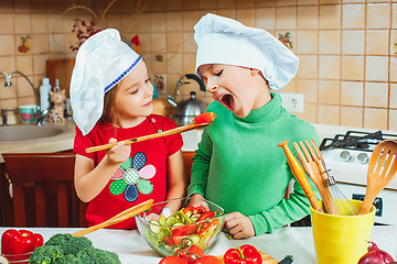 Image showing happy family funny kids are preparing the a fresh vegetable salad in the kitchen