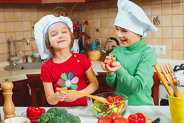 Image showing happy family funny kids are preparing the a fresh vegetable salad in the kitchen