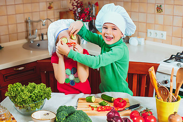 Image showing happy family funny kids are preparing the a fresh vegetable salad in the kitchen