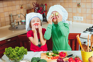 Image showing happy family funny kids are preparing the a fresh vegetable salad in the kitchen