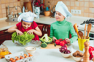 Image showing happy family funny kids are preparing the a fresh vegetable salad in the kitchen