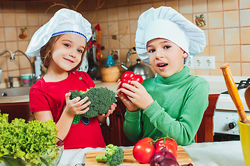 Image showing happy family funny kids are preparing the a fresh vegetable salad in the kitchen