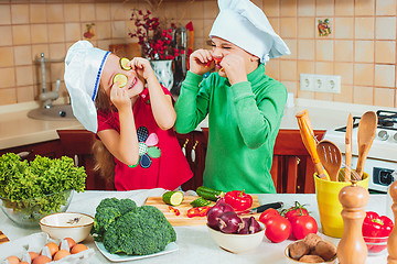 Image showing happy family funny kids are preparing the a fresh vegetable salad in the kitchen