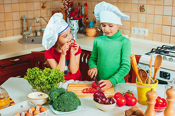 Image showing happy family funny kids are preparing the a fresh vegetable salad in the kitchen