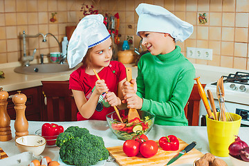 Image showing happy family funny kids are preparing the a fresh vegetable salad in the kitchen