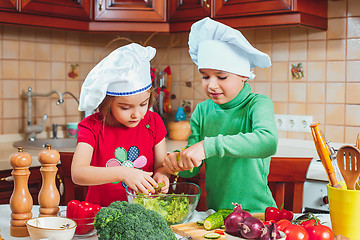 Image showing happy family funny kids are preparing the a fresh vegetable salad in the kitchen