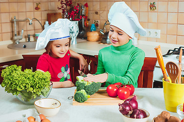 Image showing happy family funny kids are preparing the a fresh vegetable salad in the kitchen