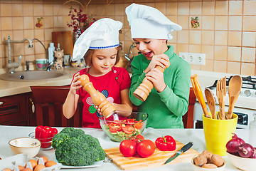 Image showing happy family funny kids are preparing the a fresh vegetable salad in the kitchen