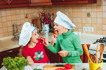 Image showing happy family funny kids are preparing the a fresh vegetable salad in the kitchen