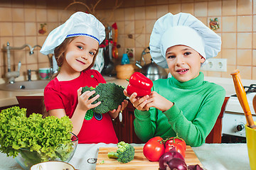 Image showing happy family funny kids are preparing the a fresh vegetable salad in the kitchen