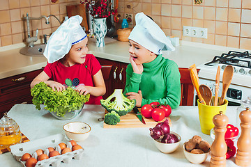 Image showing happy family funny kids are preparing the a fresh vegetable salad in the kitchen