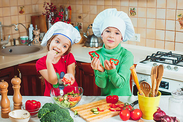 Image showing happy family funny kids are preparing the a fresh vegetable salad in the kitchen