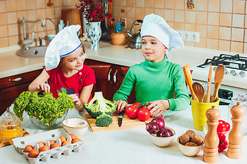 Image showing happy family funny kids are preparing the a fresh vegetable salad in the kitchen