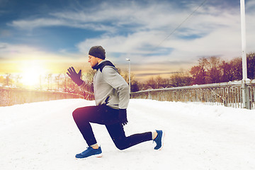 Image showing man exercising and doing squats on winter bridge