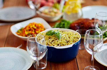 Image showing pasta with basil in bowl and other food on table