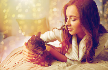 Image showing happy young woman with cat lying in bed at home